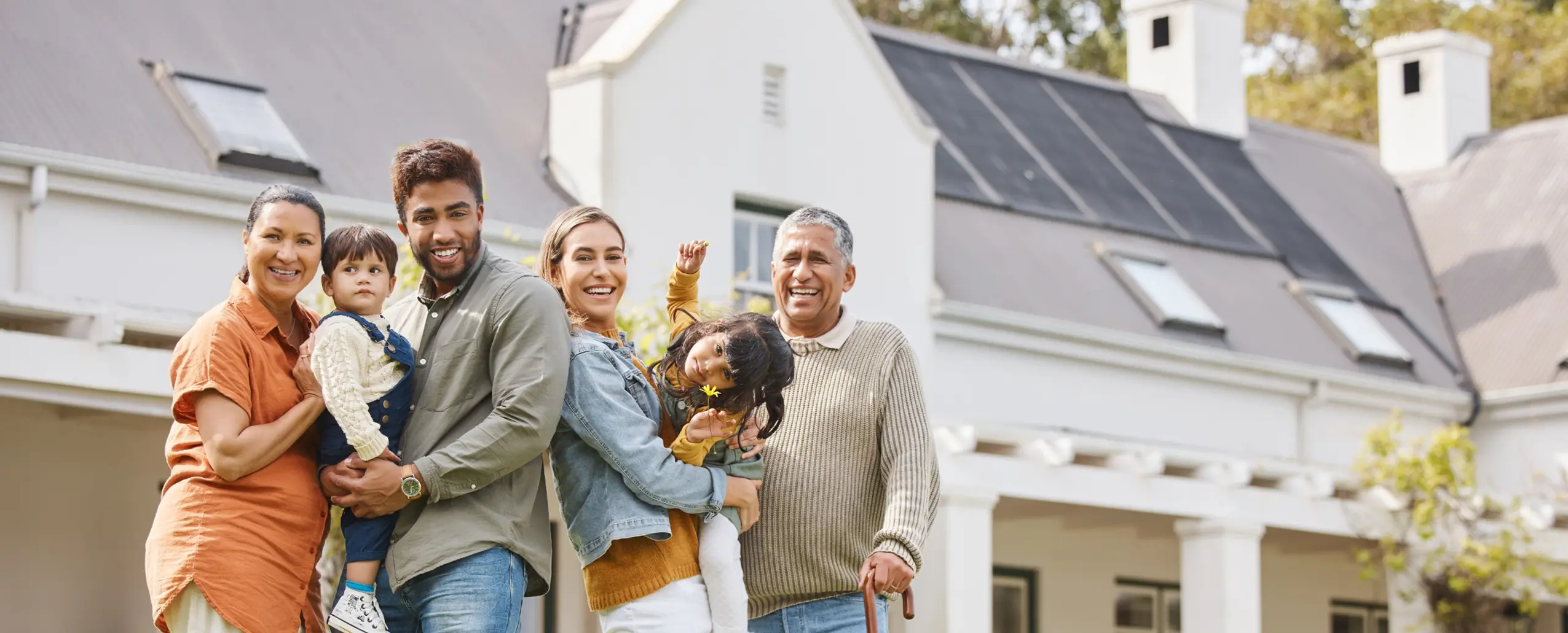 Family who joined a solar co-op standing in front of their house  that has solar roof tiles